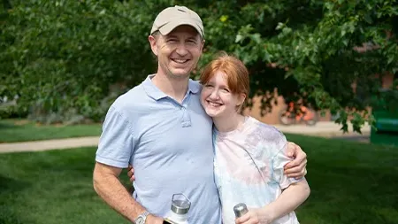 Student smiling with dad outside.